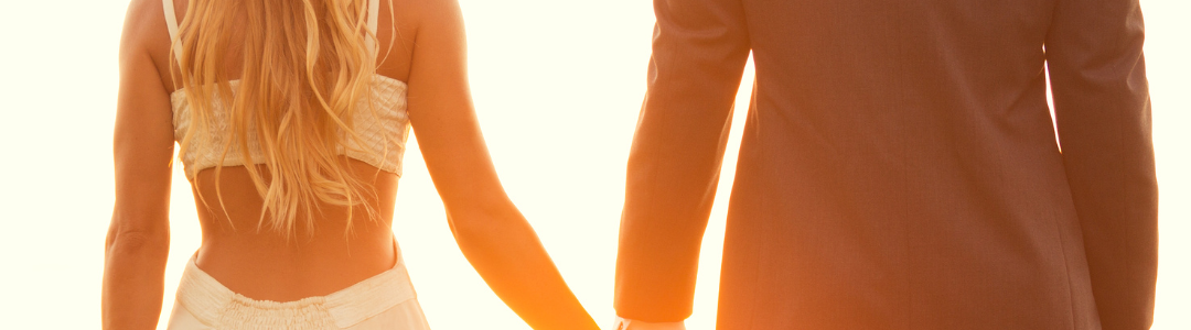 tendencias Pareja de espaldas tomada de la mano al atardecer junto al mar.