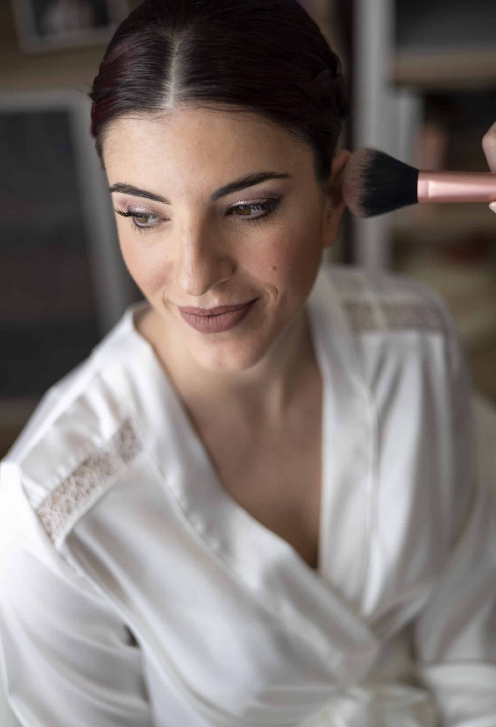Alba y Gian 01825 Maquilladora aplicando maquillaje a una novia en un ambiente íntimo y acogedor.