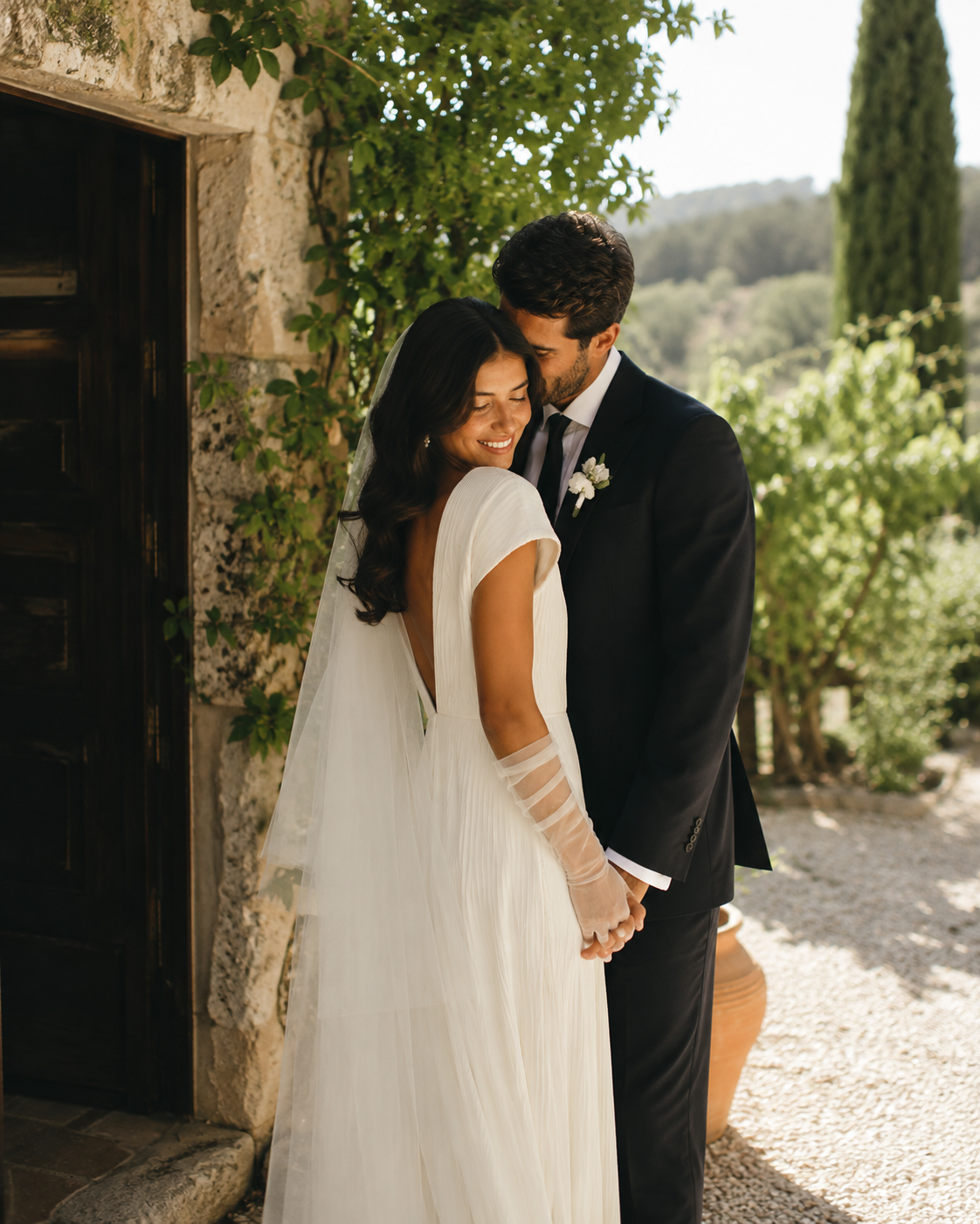 ed133532-095a-4dee-96ee-3a8ad26945dd Pareja de recién casados abrazándose en un entorno natural, con la novia luciendo un vestido elegante y velo.