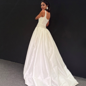 Novia de espaldas luciendo un elegante vestido blanco con detalles en la parte superior.