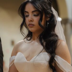 Novia con vestido blanco y tiara, peinado con ondas sueltas y maquillaje natural en ceremonia.