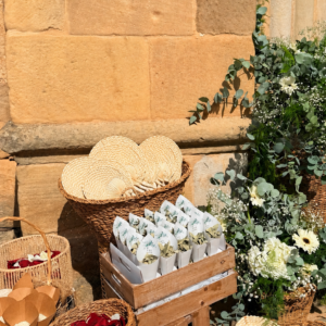 Cestos con abanicos de paja y flores blancas junto a muro de piedra.