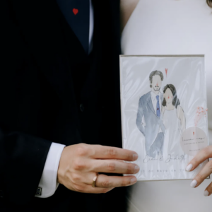 Pareja vestida de boda sostiene ilustración personalizada de ellos mismos.