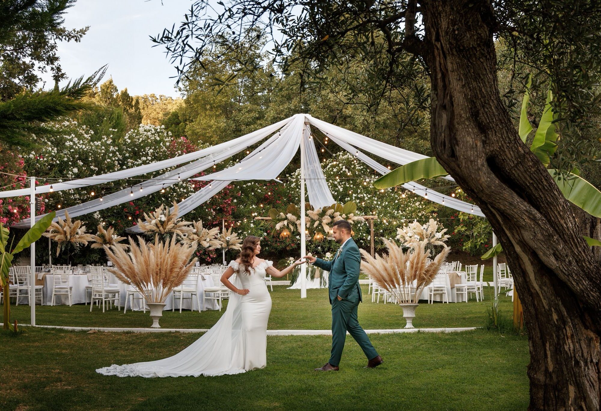 IMG_2403 Novios caminando bajo un dosel blanco en un jardín con sillas y decoración natural para boda.